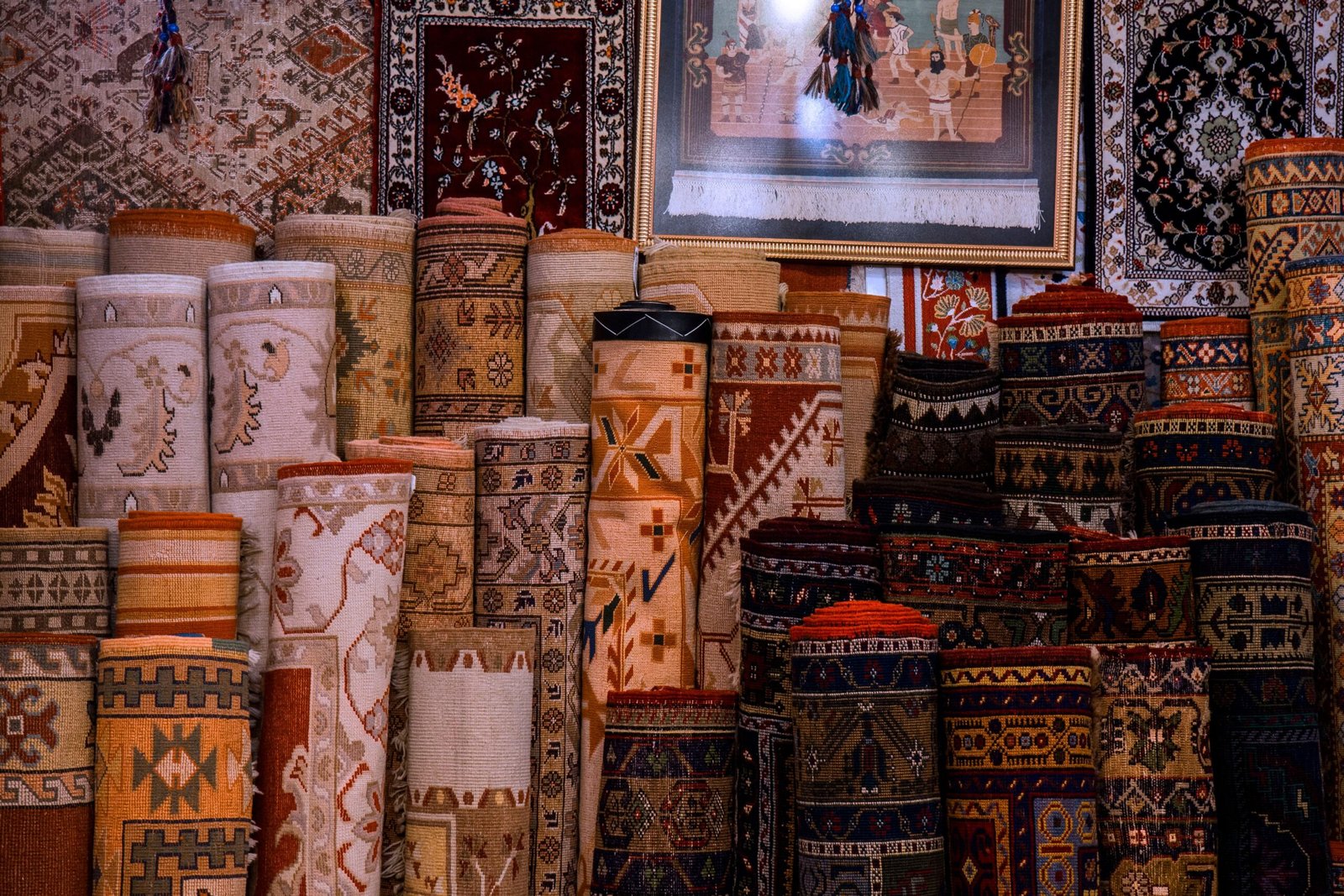 Vibrant collection of traditional rolled carpets on display in a cultural bazaar setting.